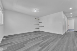 Open-concept room featuring wood-finish flooring, white walls, and a contemporary ceiling fixture - 
