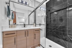 Bathroom featuring a dark tiled shower with clear glass enclosure and a single vanity - 