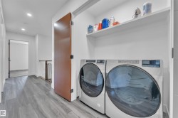Dedicated laundry area featuring front-loading machines and integrated shelving - 