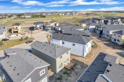 Newly constructed residence featuring a light olive exterior, a dark gray asphalt shingle roof, and multiple windows - 