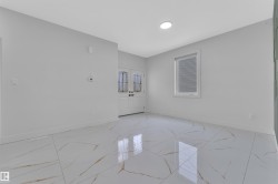 Bright interior space featuring large format white tile flooring with gold veining, white walls, and a recessed ceiling light - 