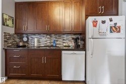 Kitchen featuring rich wood-finish cabinetry, dark countertops, and a mosaic tile backsplash - 