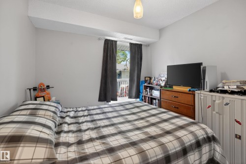 Bedroom featuring white walls, a textured ceiling, a built-in light fixture, and a glass sliding door providing outdoor access - 35 3111 142 Avenue, Edmonton, AB 