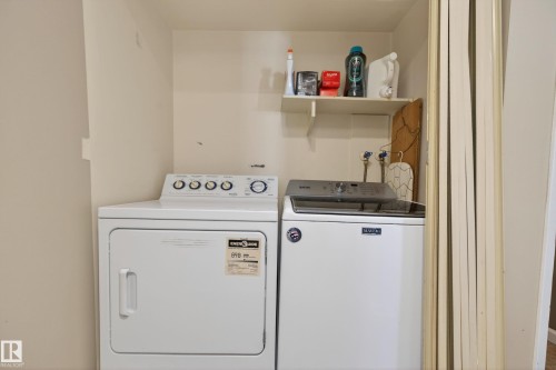 Dedicated laundry alcove featuring a white top-load washing machine and a white front-load dryer - 35 3111 142 Avenue, Edmonton, AB 