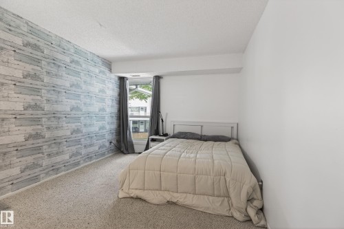 Spacious room featuring a textured accent wall, light-colored carpeting, a window with curtains, and ample natural light - 35 3111 142 Avenue, Edmonton, AB 