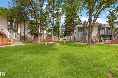 Expansive green space featuring a manicured lawn, mature trees, and a wooden bench - 35 3111 142 Avenue, Edmonton, AB 