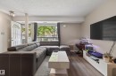 Living area featuring wood-finish flooring, a large window with exterior railing, a white entry door with an arched transom, and track lighting - 35 3111 142 Avenue, Edmonton, AB 