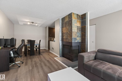 Spacious living area featuring wood-finish flooring, a tiled fireplace with a raised hearth, and recessed ceiling lighting - 35 3111 142 Avenue, Edmonton, AB 