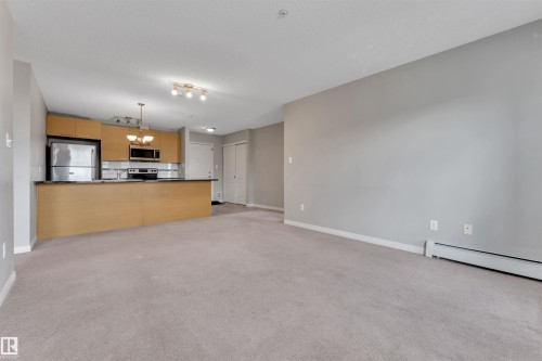 Open-concept living area with neutral carpeting and light gray walls - 3302 9351 Simpson Drive, Edmonton, AB 
