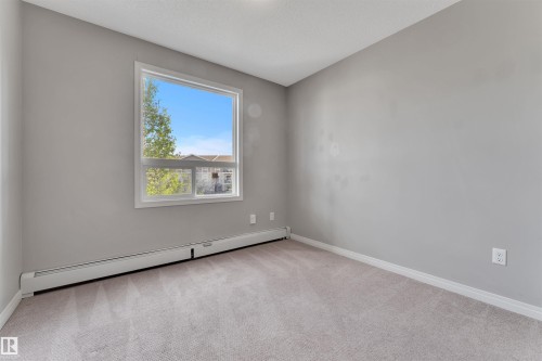 Neutral-toned room featuring a large window with white trim, light gray walls, and carpeting - 3302 9351 Simpson Drive, Edmonton, AB 