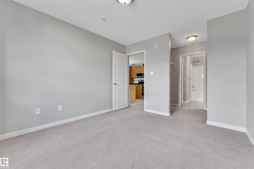 Carpeted room with light gray wall paint and white trim, featuring a flush mount ceiling light - 3302 9351 Simpson Drive, Edmonton, AB 