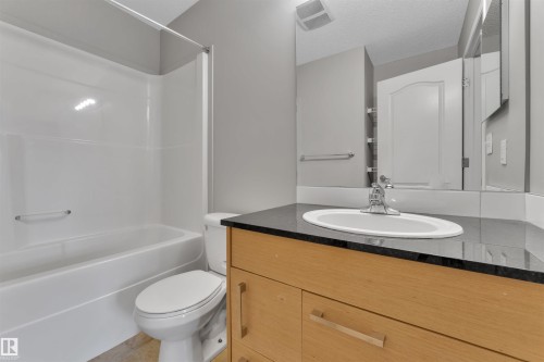 Bathroom featuring a wood-finish vanity with a dark countertop and an undermount sink - 3302 9351 Simpson Drive, Edmonton, AB 