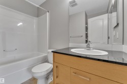Bathroom featuring a wood-finish vanity with a dark countertop and an undermount sink - 