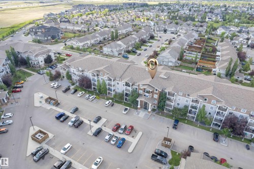 Multi-level residential building featuring exterior balconies, a dedicated parking area, and mature landscaping - 3302 9351 Simpson Drive, Edmonton, AB 