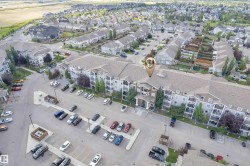 Multi-level residential building featuring exterior balconies, a dedicated parking area, and mature landscaping - 
