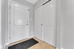Entryway featuring a white paneled door with brushed nickel hardware, light gray walls, and beige tile flooring - 