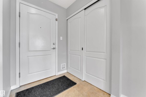 Entryway featuring a white paneled door with brushed nickel hardware, light gray walls, and beige tile flooring - 3302 9351 Simpson Drive, Edmonton, AB 