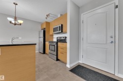 Kitchenette featuring wood-finish cabinetry, stainless steel appliances, and a dark stone-finish countertop - 
