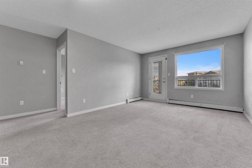 Spacious room featuring light grey carpeting, painted walls, and white baseboards - 3302 9351 Simpson Drive, Edmonton, AB 