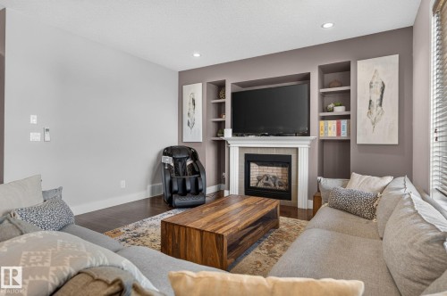 Living area featuring a fireplace with a white mantel, built-in shelving, wood-finish flooring, and recessed lighting - 14016 161 Avenue, Edmonton, AB 