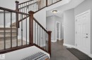 Entryway featuring a grand staircase with dark wood-finish newel posts and wrought iron balusters, complemented by light grey wall paint and white baseboards - 14016 161 Avenue, Edmonton, AB 