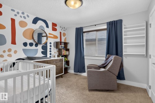 Accent wall featuring a geometric pattern, large window with blinds, carpeted flooring, and a built-in wall shelf - 14016 161 Avenue, Edmonton, AB 