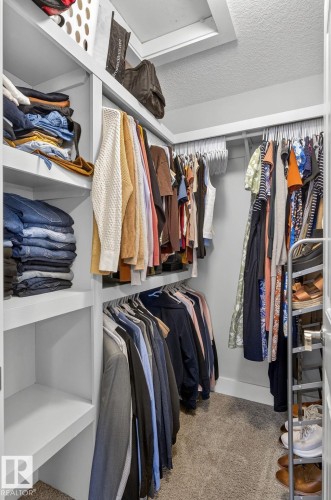 Walk-in closet featuring built-in shelving, multiple hanging rods, and carpet flooring - 14016 161 Avenue, Edmonton, AB 