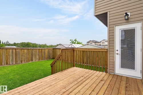 Spacious outdoor deck with natural wood flooring and railing, featuring direct access to the interior via a white paneled door with a full-view storm screen - 14016 161 Avenue, Edmonton, AB 