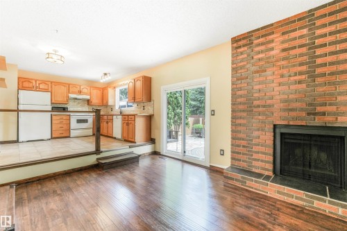 Sunken living room with brick fireplace and sliding patio door to backyard. - 2921 130 Avenue, Edmonton, AB 