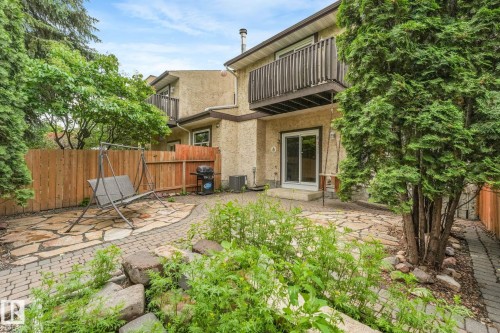 Private backyard featuring a stone patio, brick paver pathway, and mature trees - 2921 130 Avenue, Edmonton, AB 