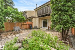 Private backyard featuring a stone patio, brick paver pathway, and mature trees - 