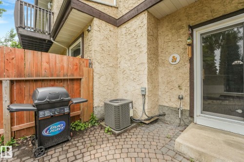 Outdoor patio space featuring paver stone flooring, stucco exterior, and a sliding glass door. Central Air Conditioning included in the sale. - 2921 130 Avenue, Edmonton, AB 
