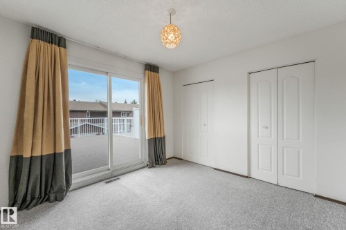 White-painted room featuring light gray carpeting and a sliding glass door opening to an outdoor deck - 2921 130 Avenue, Edmonton, AB 
