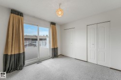 White-painted room featuring light gray carpeting and a sliding glass door opening to an outdoor deck - 