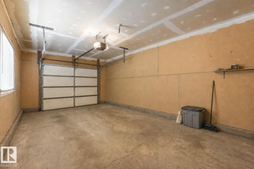 Spacious garage featuring a concrete floor, overhead lighting, and an automatic garage door opener - 2921 130 Avenue, Edmonton, AB 