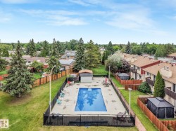 Private outdoor swimming pool with surrounding concrete deck, black metal fencing, and a small pool house - 