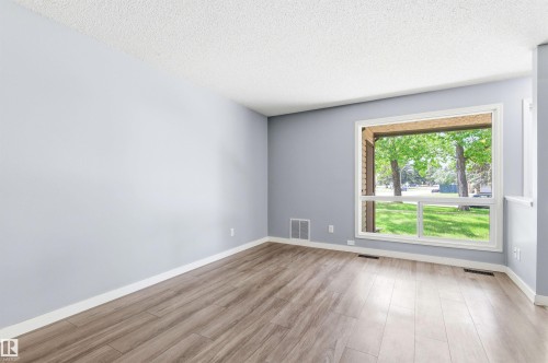 Spacious room featuring wood-finish flooring, a large picture window, light blue painted walls, and white trim - 2005 Saddleback Road, Edmonton, AB - Indoor Photo Showing Other Room