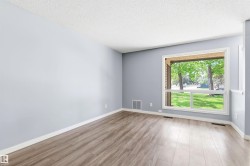 Spacious room featuring wood-finish flooring, a large picture window, light blue painted walls, and white trim - 