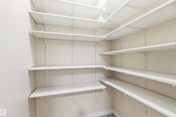 Walk-in pantry featuring expansive shelving, adjustable white wire shelving, light-toned wall paint, and L-shaped configuration - 