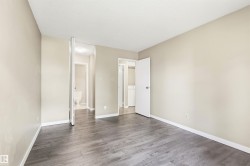Spacious room featuring wood-finish flooring, neutral-toned walls, and white baseboards - 