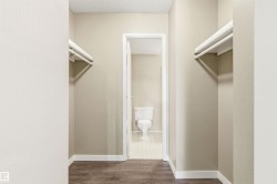 Interior hallway featuring wood-finish flooring, light neutral wall paint, and white baseboards - 