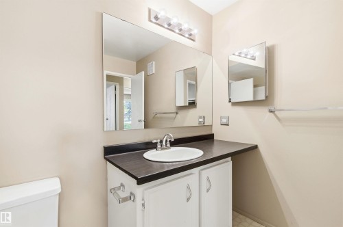 Vanity with a white oval sink, dark countertop, and brushed nickel faucet - 2005 Saddleback Road, Edmonton, AB - Indoor Photo Showing Bathroom