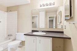 Bathroom vanity with an integrated sink, dark countertop, and white cabinetry - 