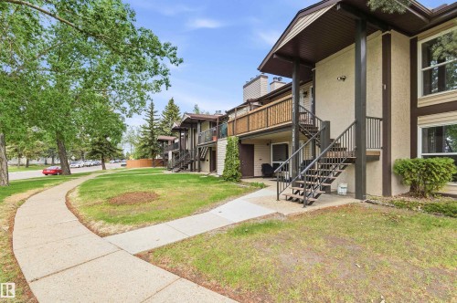 Multi-level residential building featuring a neutral-toned exterior with dark brown trim and individual exterior staircases - 2005 Saddleback Road, Edmonton, AB - Outdoor
