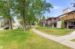 Exterior view featuring a multi-story building with light-colored siding and dark trim - 