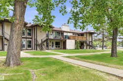 Multi-story residential building featuring light-colored siding, brown trim, and a dark shingle roof - 