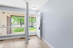 Entryway featuring wood-finish flooring, light grey painted walls, white trim, and a white front door with decorative lites - 