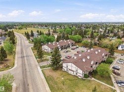 Multi-unit residential buildings with brown shingle roofs, off-white siding, and dark trim - 