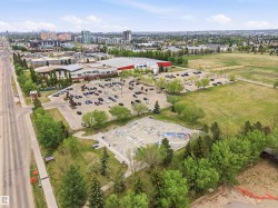 Aerial perspective showcasing a large commercial structure with an expansive parking area, surrounded by green spaces and mature trees - 