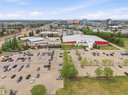 Large parking facility with multiple vehicle spaces, surrounding two prominent commercial buildings - 